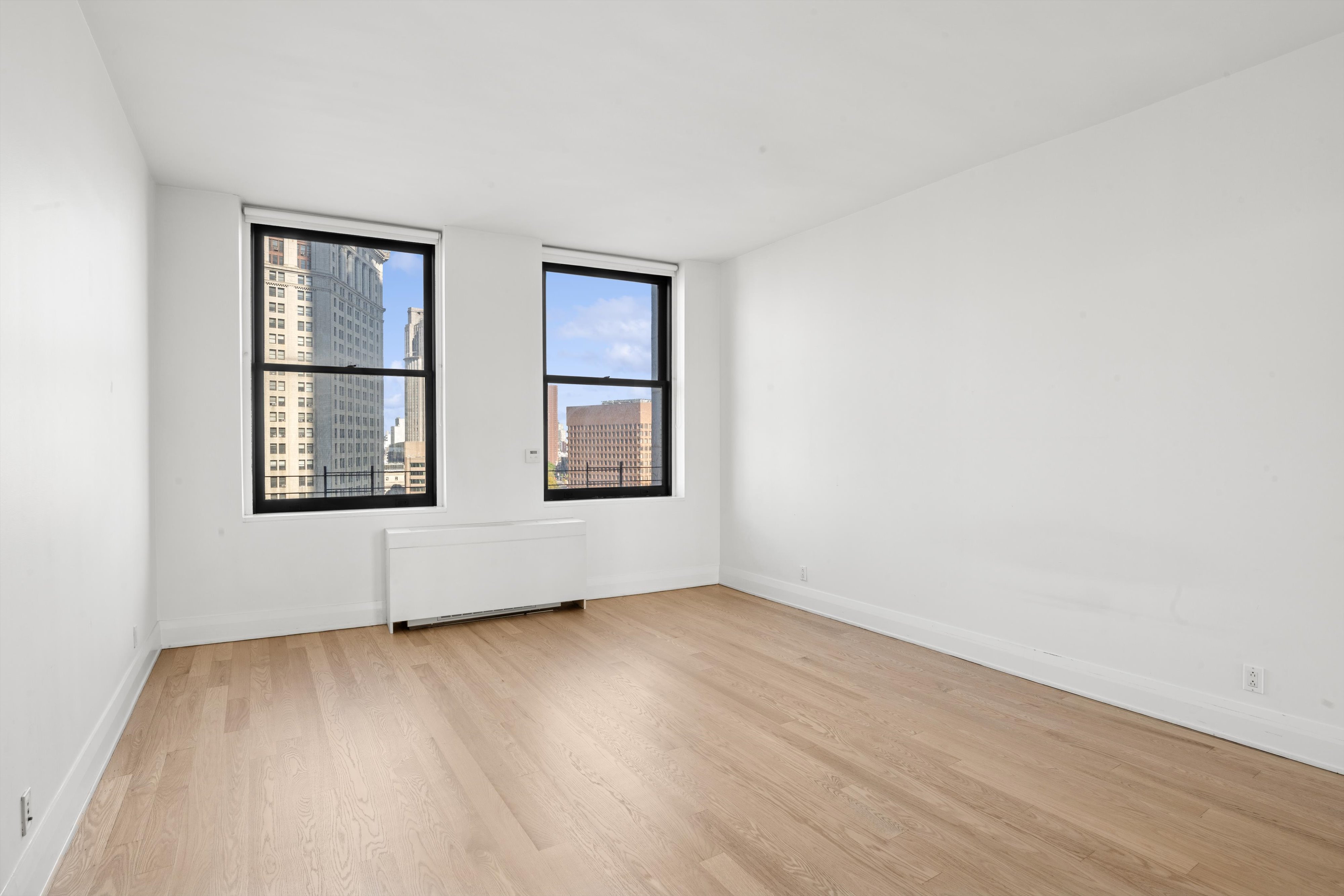 150 Nassau Street, Unit 11B Manhattan, NY 10038 - Photo 5 of 17 an empty room with wooden floor and windows