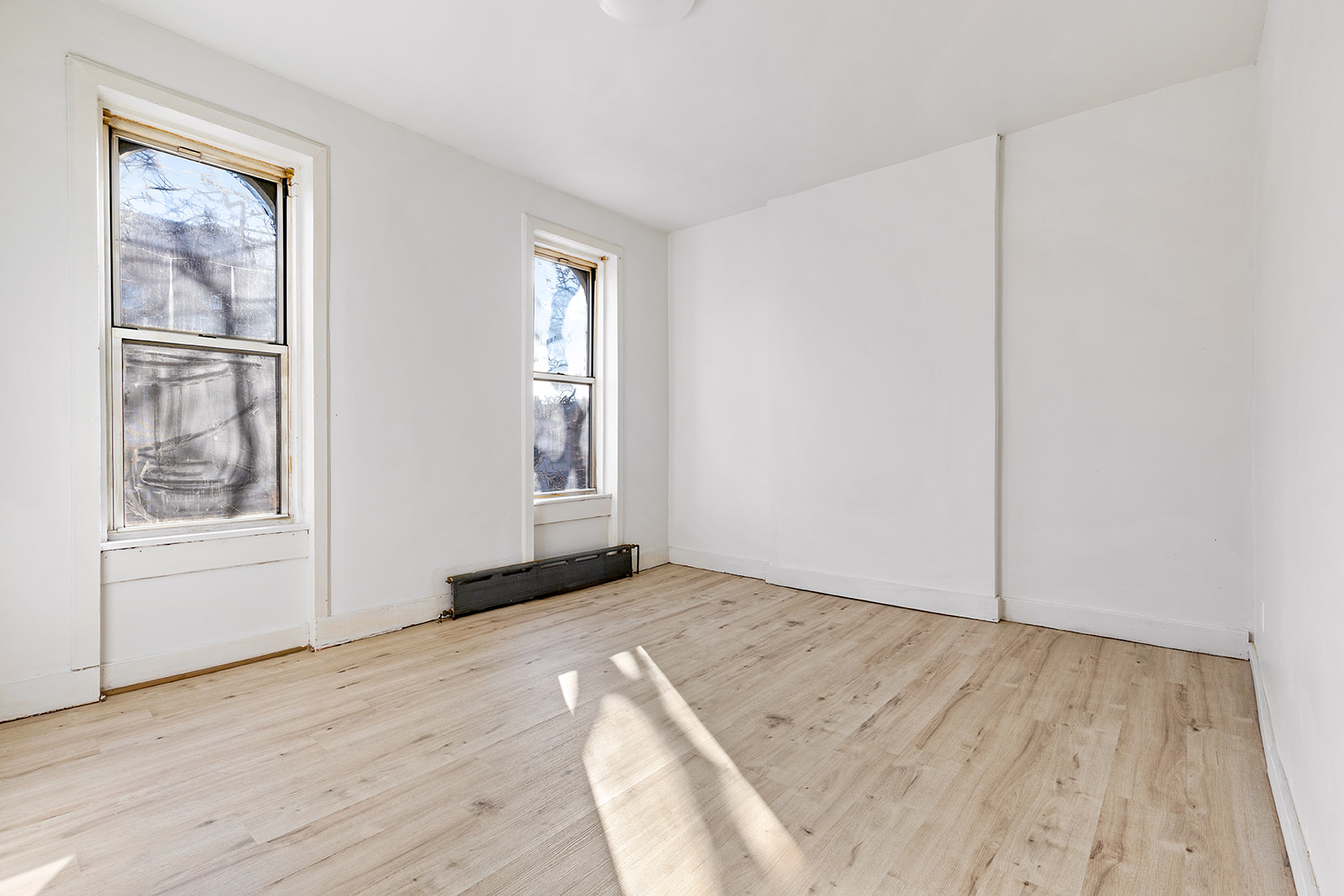208 Lewis Avenue, Unit 4 Brooklyn, NY 11221 - Photo 2 of 7 an empty room with wooden floor and windows