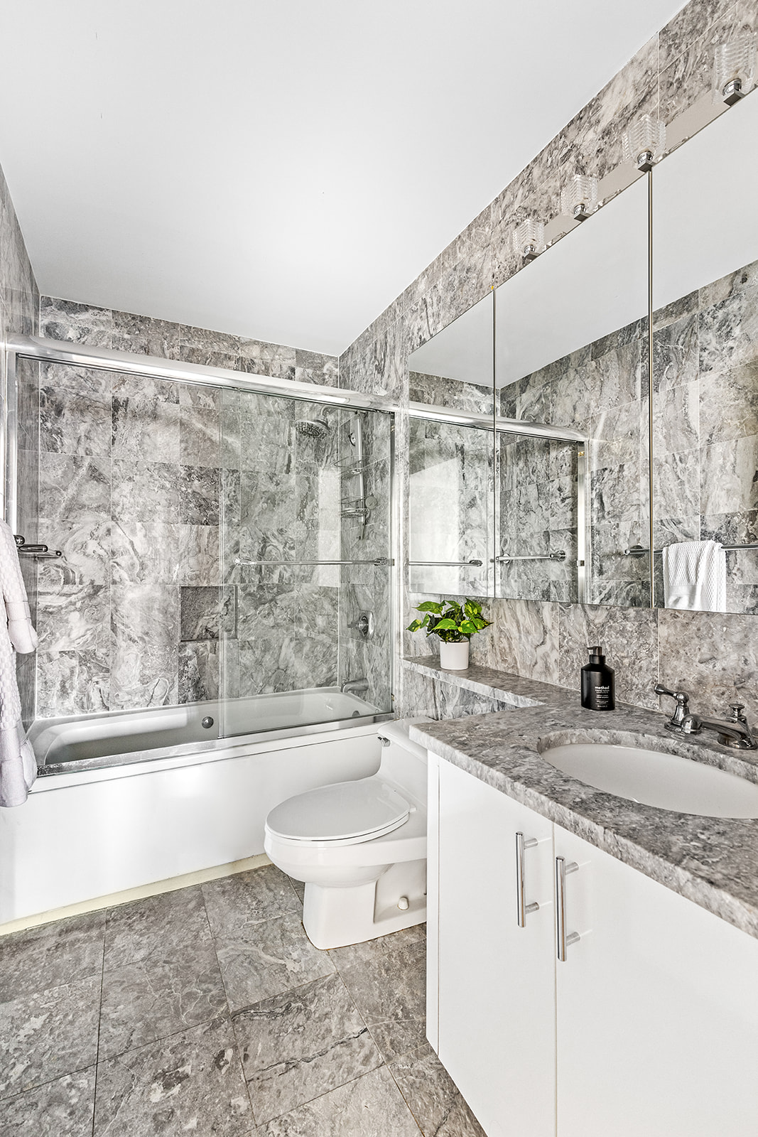 350 East 72nd Street, Unit 12A Manhattan, NY 10021 - Photo 5 of 9 a bathroom with a granite countertop bathtub sink vanity mirror and toilet