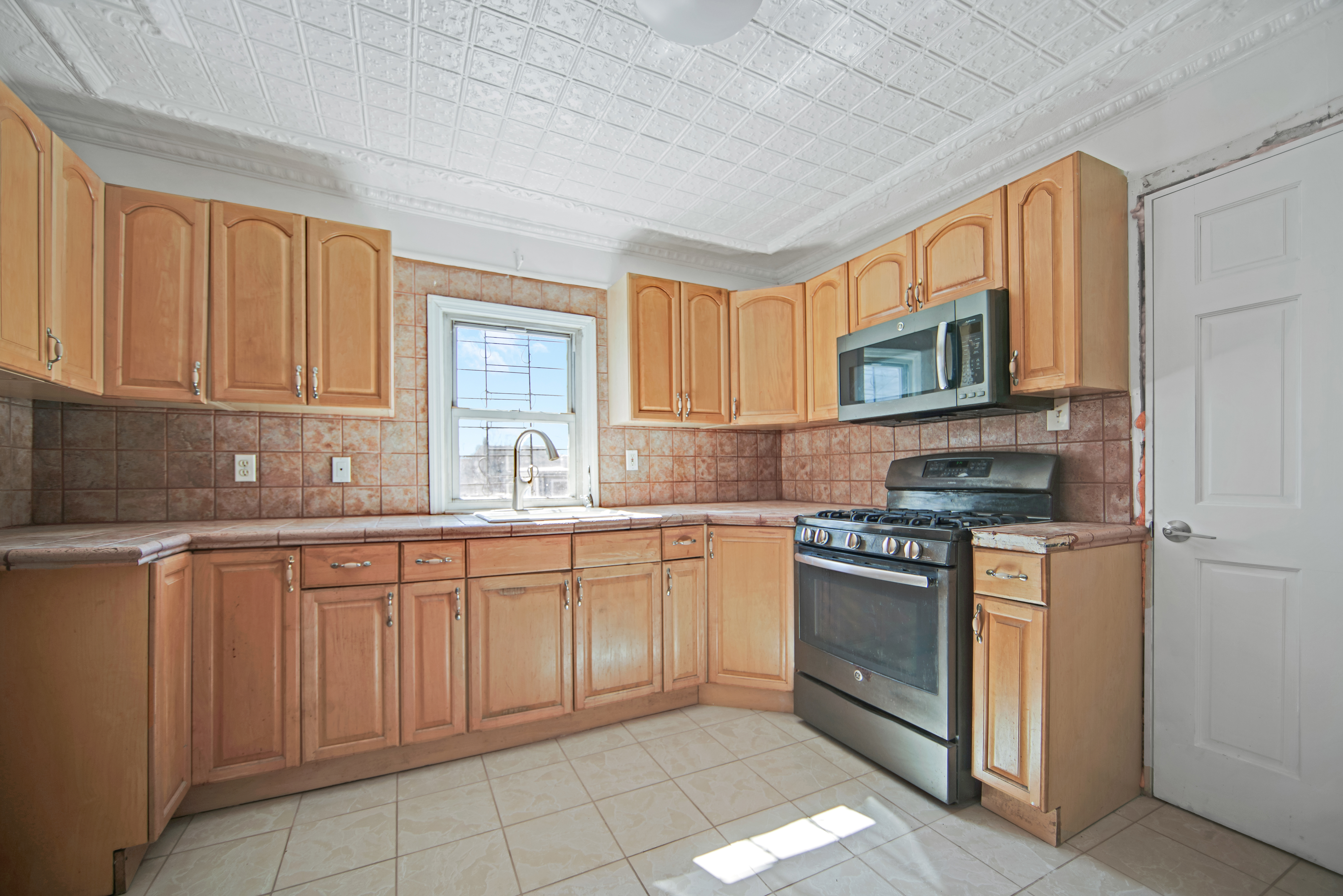 296 17th Street Brooklyn, NY 11215 - Photo 3 of 8 a kitchen with cabinets appliances a sink and a window