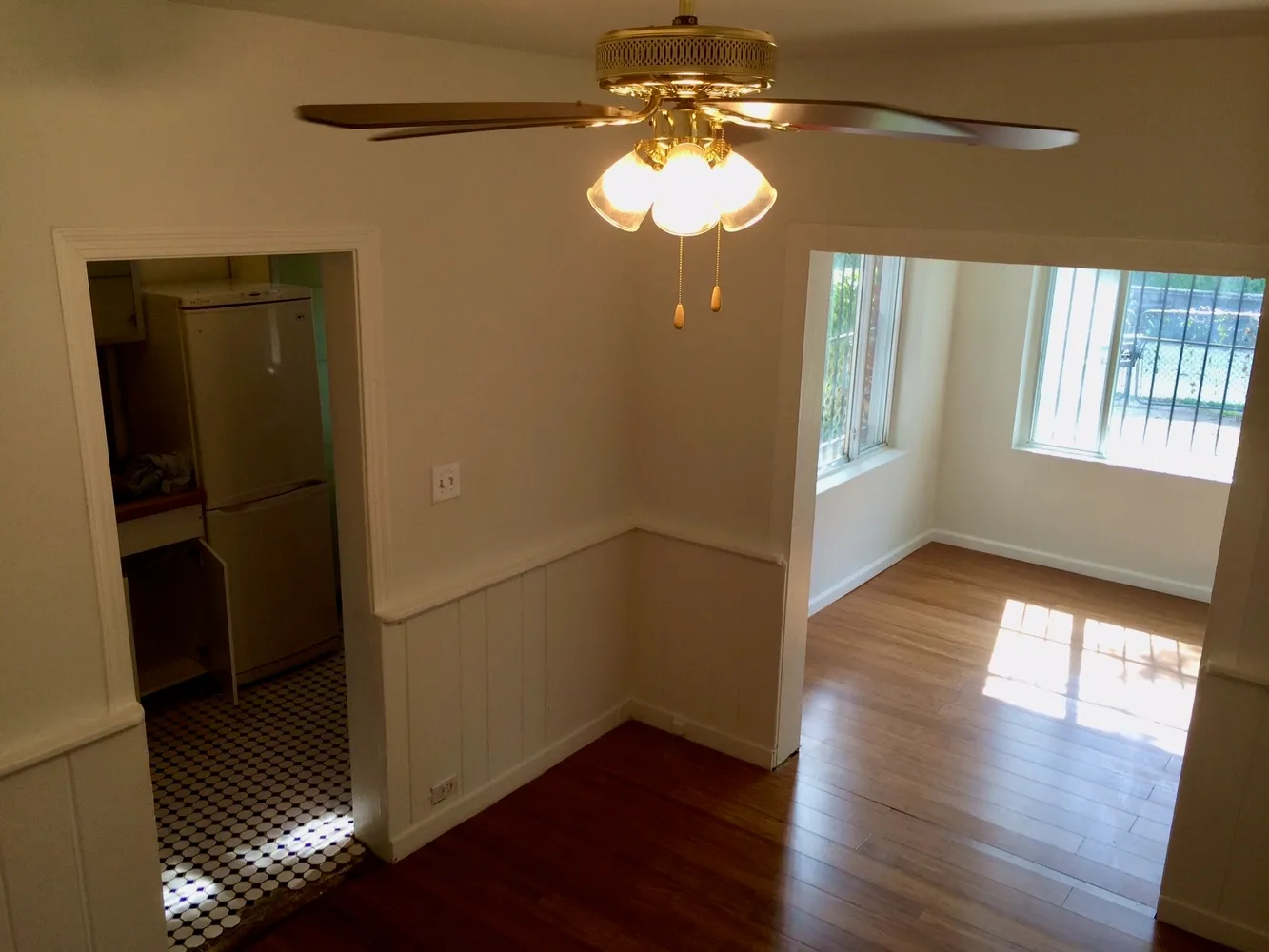 a view of empty room with wooden floor and fan