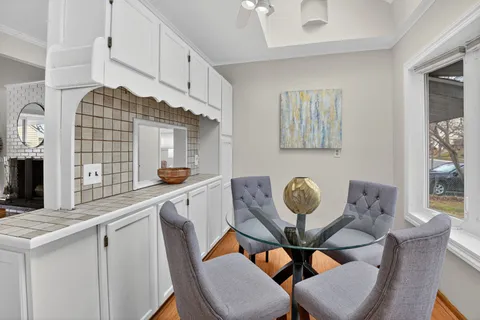 a kitchen with stainless steel appliances kitchen island granite countertop a dining table chairs and a refrigerator