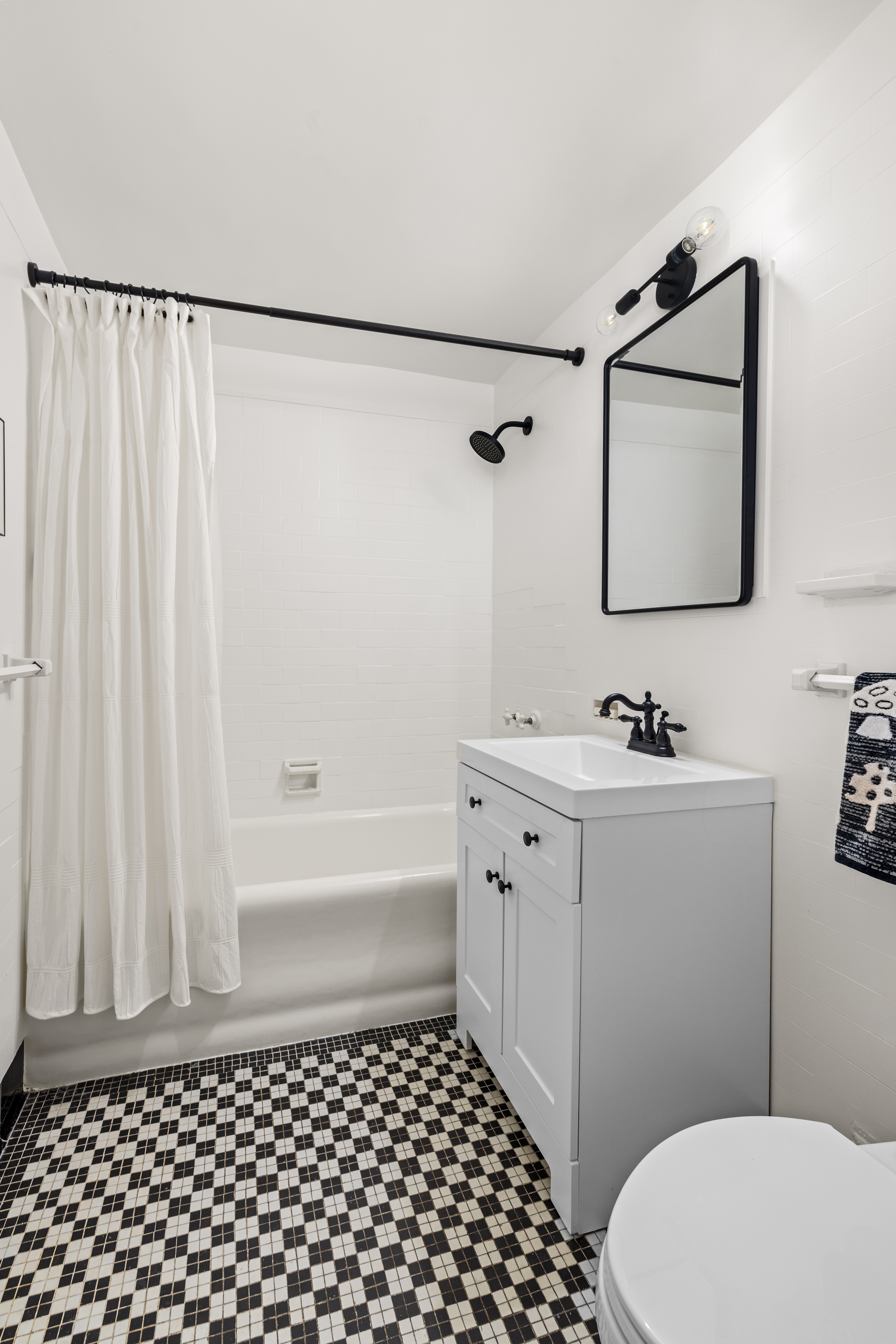 201 West 16th Street, Unit 8F Manhattan, NY 10011 - Photo 5 of 11 a bathroom with a sink a toilet a shower curtain and a bath tub