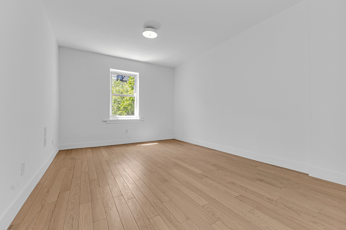 1050 Sterling Place Brooklyn, NY 11213 - Photo 21 of 23 an empty room with wooden floor and window