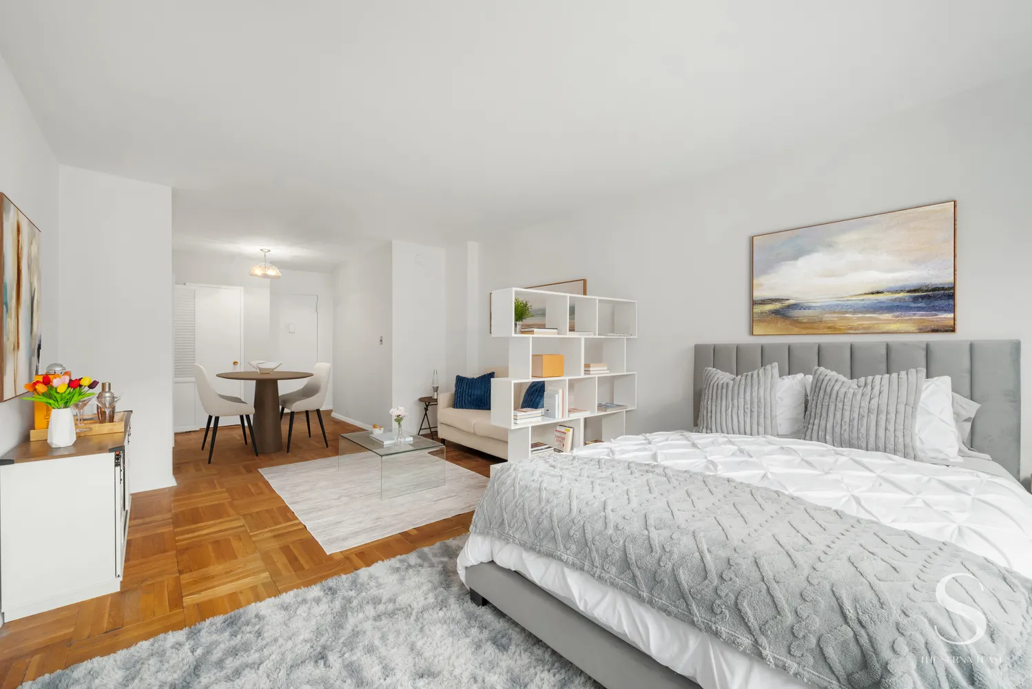 a bedroom with a bed a table and kitchen view