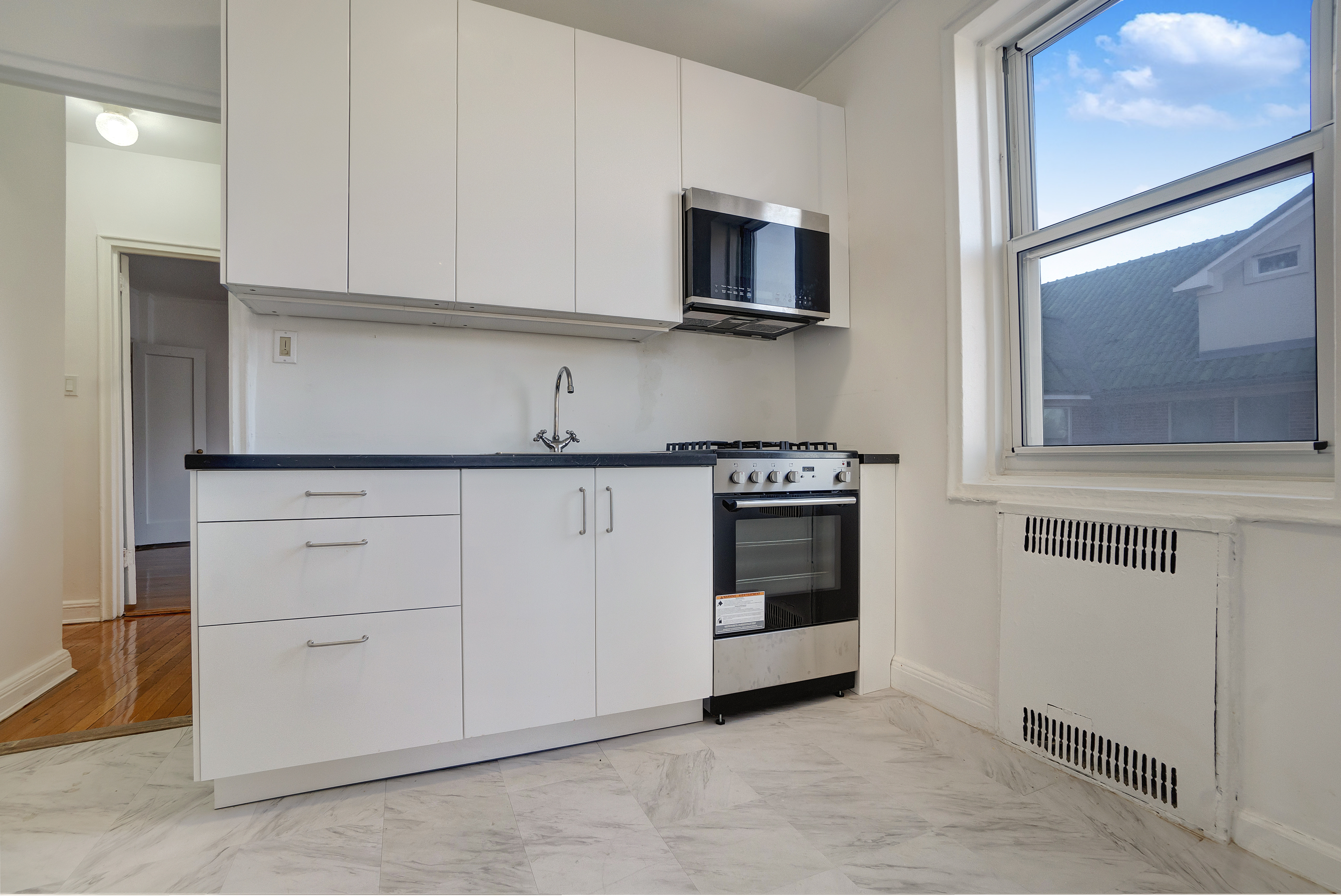 286 Corbin Place, Unit 2A Brooklyn, NY 11235 - Photo 3 of 13 a kitchen with white cabinets stainless steel appliances and sink