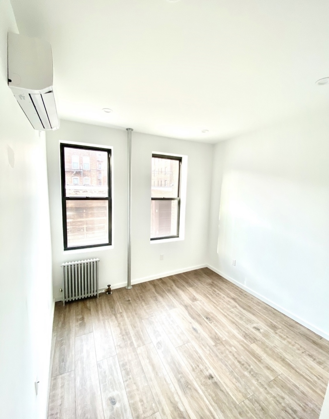 31-14 36th Street, Unit 3F Queens, NY 11106 - Photo 7 of 11 an empty room with wooden floor and windows
