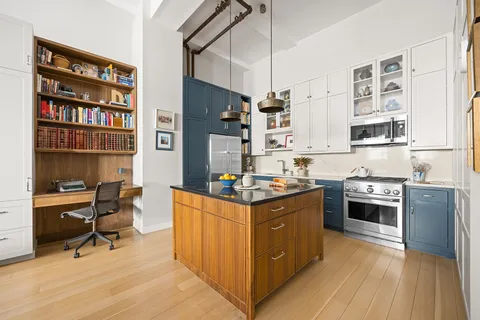 a kitchen with stainless steel appliances a stove top oven a chimney and a bookshelf