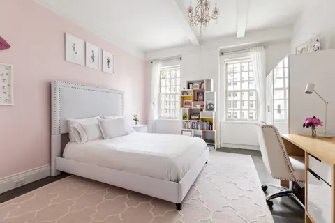 a bedroom with a large bed a chandelier and a window