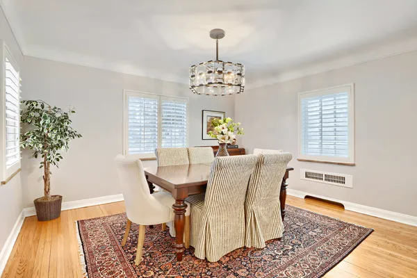 a dining room with wooden floor a chandelier a wooden table and chairs