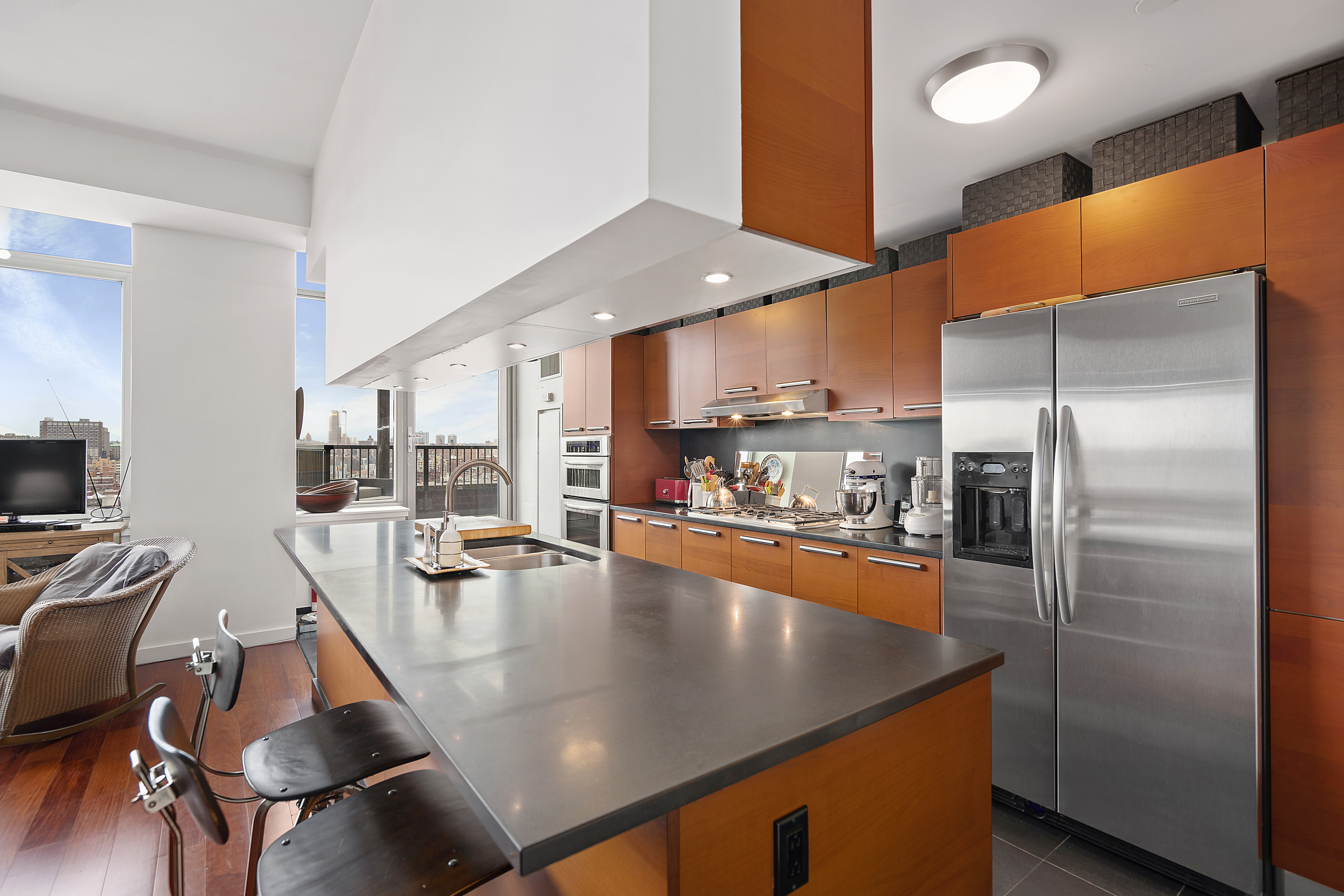 1485 5th Avenue, Unit 18/19H Manhattan, NY 10035 - Photo 6 of 21 a kitchen with stainless steel appliances granite countertop a refrigerator a stove and a sink with chandelier