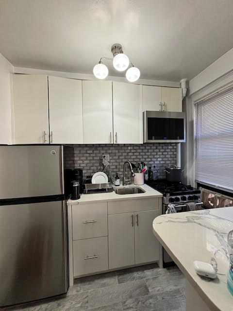 319 East 50th Street, Unit 10L Manhattan, NY 10022 - Photo 4 of 11 a kitchen with stainless steel appliances a sink stove and refrigerator