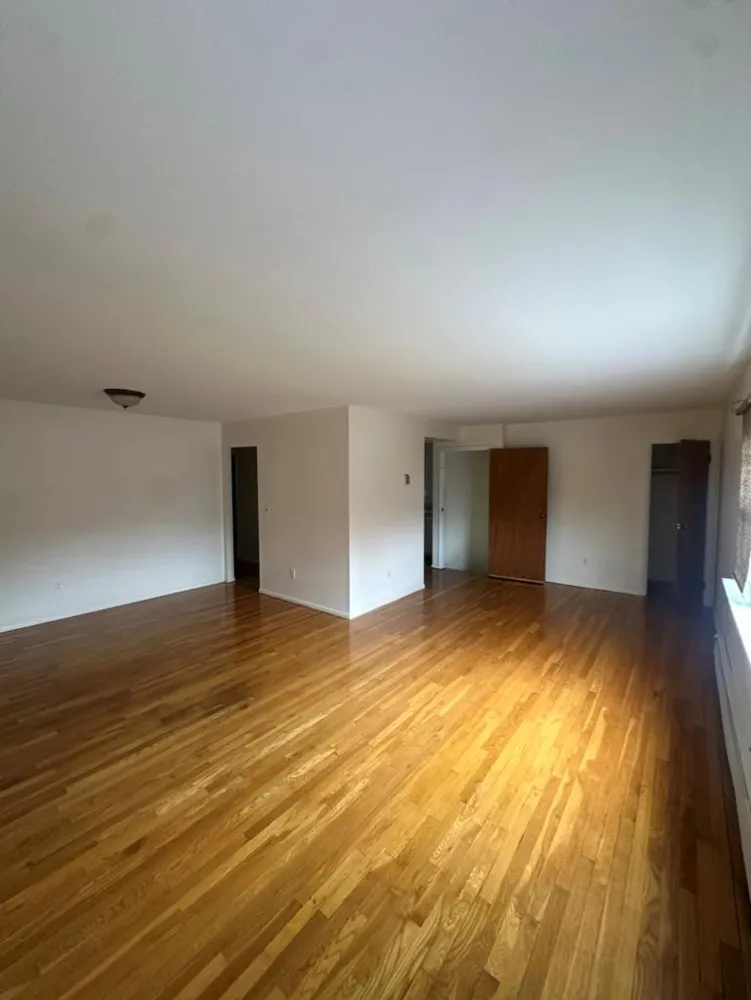 a view of an empty room and window and wooden floor