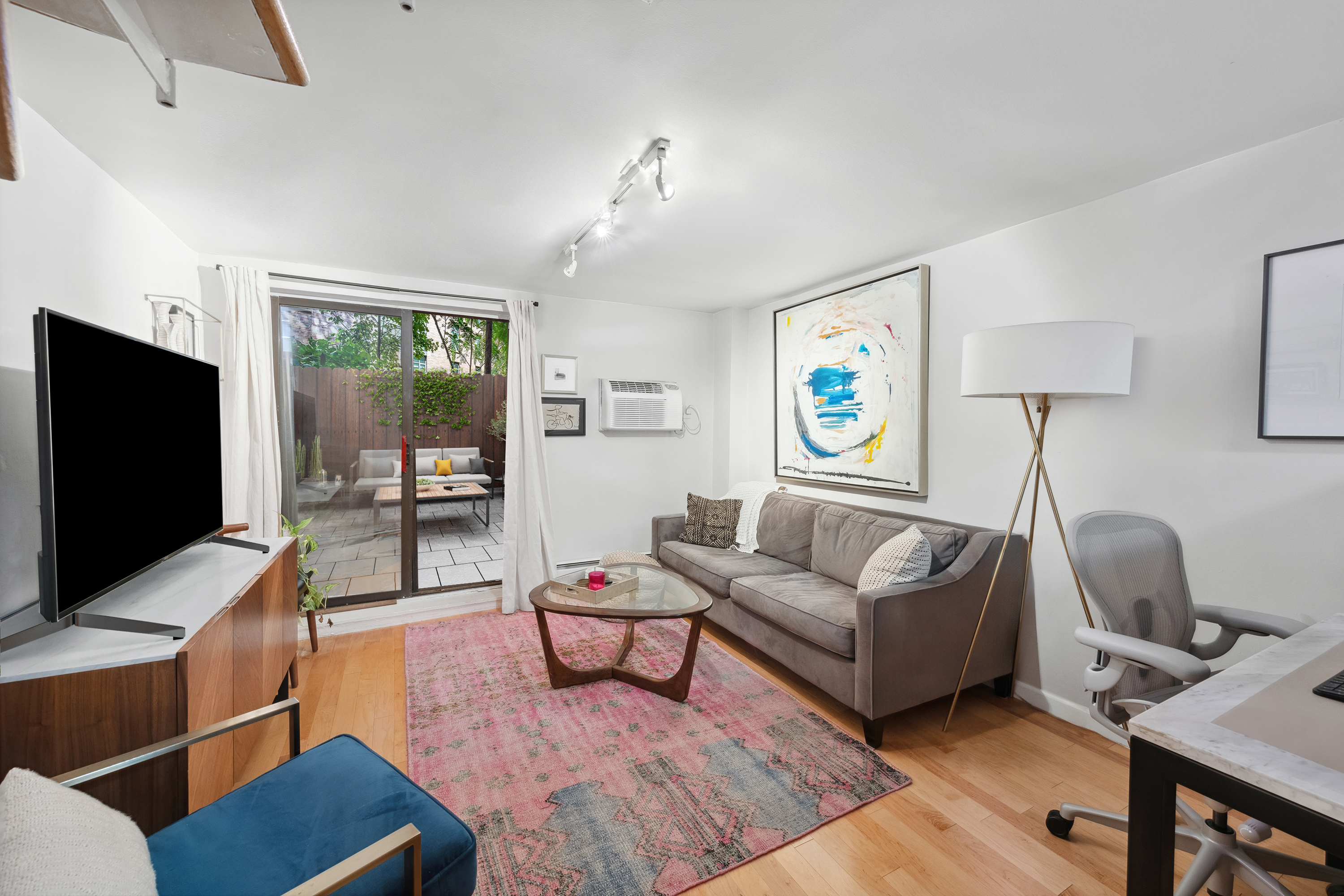211 Thompson Street, Unit GLD Manhattan, NY 10012 - Photo 2 of 10 a living room with furniture and a flat screen tv