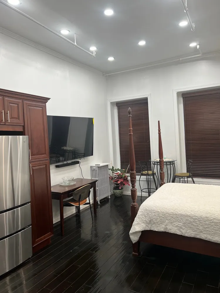 a bedroom with bed table and flat screen tv