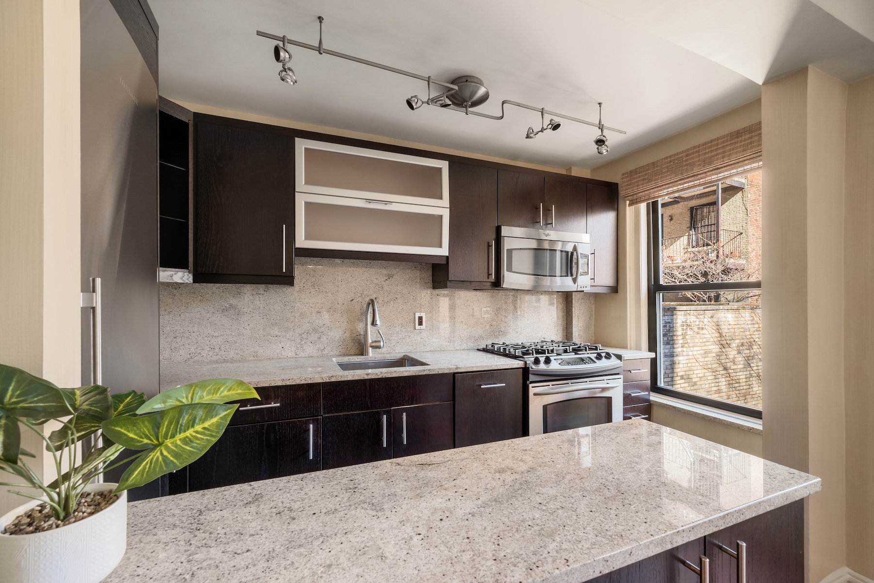 319 East 50th Street, Unit 4H Manhattan, NY 10022 - Photo 4 of 9 a kitchen with stainless steel appliances kitchen island granite countertop a sink a stove and a wooden cabinets