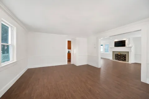 a view of a livingroom with wooden floor and a fireplace