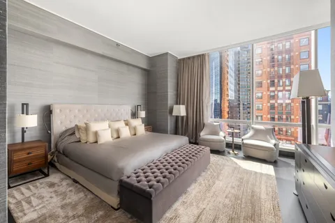 a bedroom with a bed couch and a large window