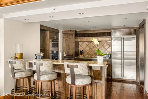 a kitchen with stainless steel appliances a dining table chairs and a large window
