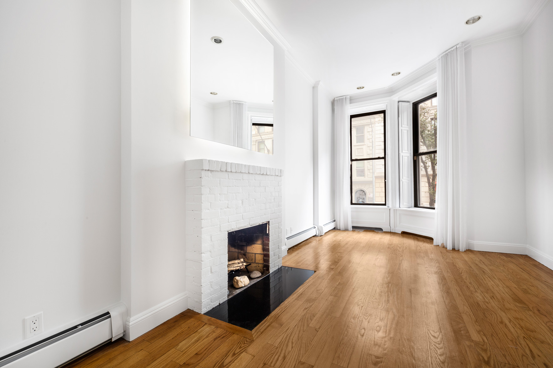 34 East 64th Street, Unit 2 Manhattan, NY 10065 - Photo 2 of 7 a view of empty room with wooden floor and fireplace