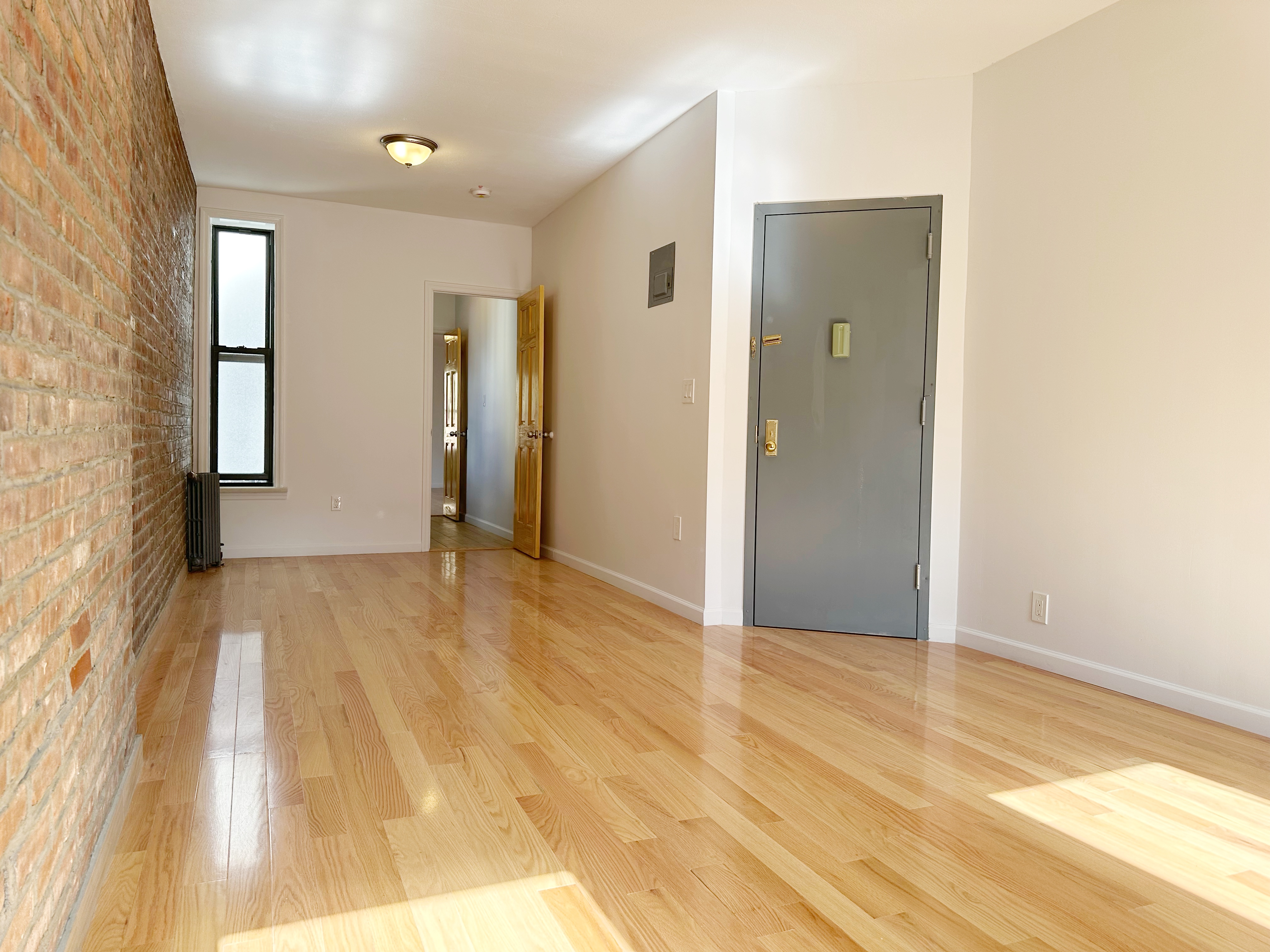 75 Madison Street, Unit 9 Manhattan, NY 10002 - Photo 3 of 6 a view of empty room with wooden floor and fan