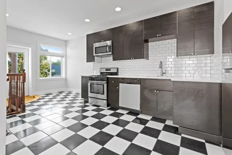 a kitchen with a checkered floor and white cabinets