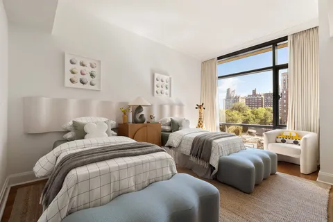 a bedroom with two beds and a large window with wooden floor