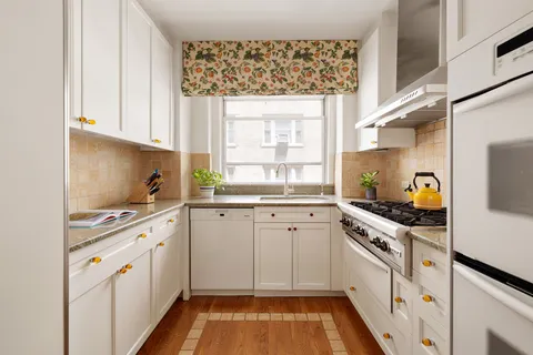 a kitchen with white cabinets appliances and a window