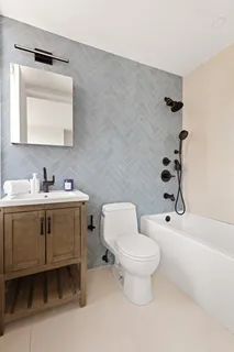 a bathroom with a toilet sink vanity tub and mirror