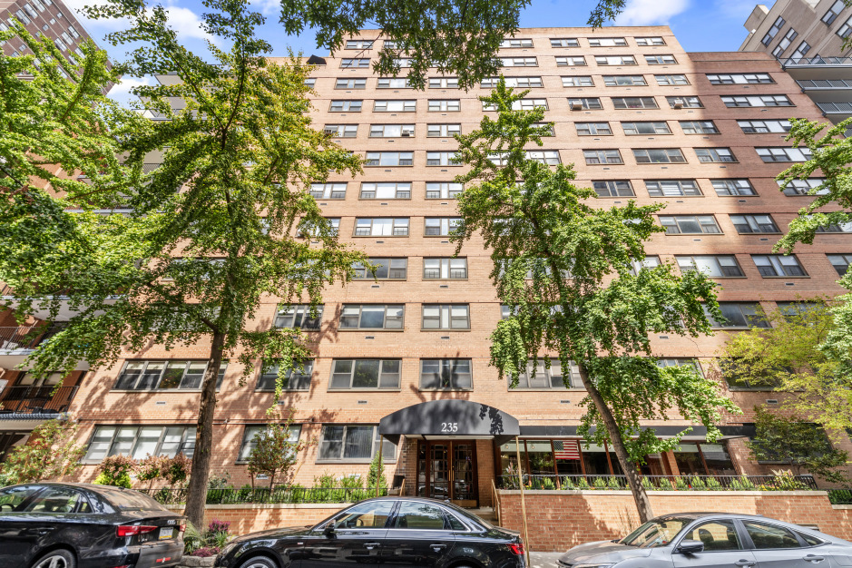 235 East 87th Street, Unit 10B Manhattan, NY 10128 - Photo 10 of 12 a front view of a building with lot of cars and trees