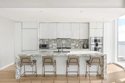 a kitchen with stainless steel appliances granite countertop a white cabinets and chairs
