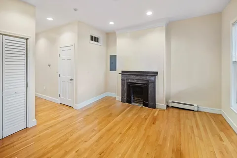 a view of empty room with wooden floor and fireplace