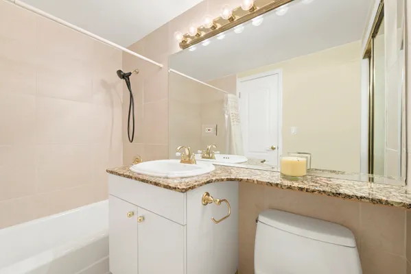 a bathroom with a granite countertop sink a mirror and a bathtub
