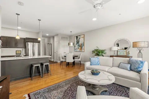 a living room with furniture a rug kitchen view and a chandelier