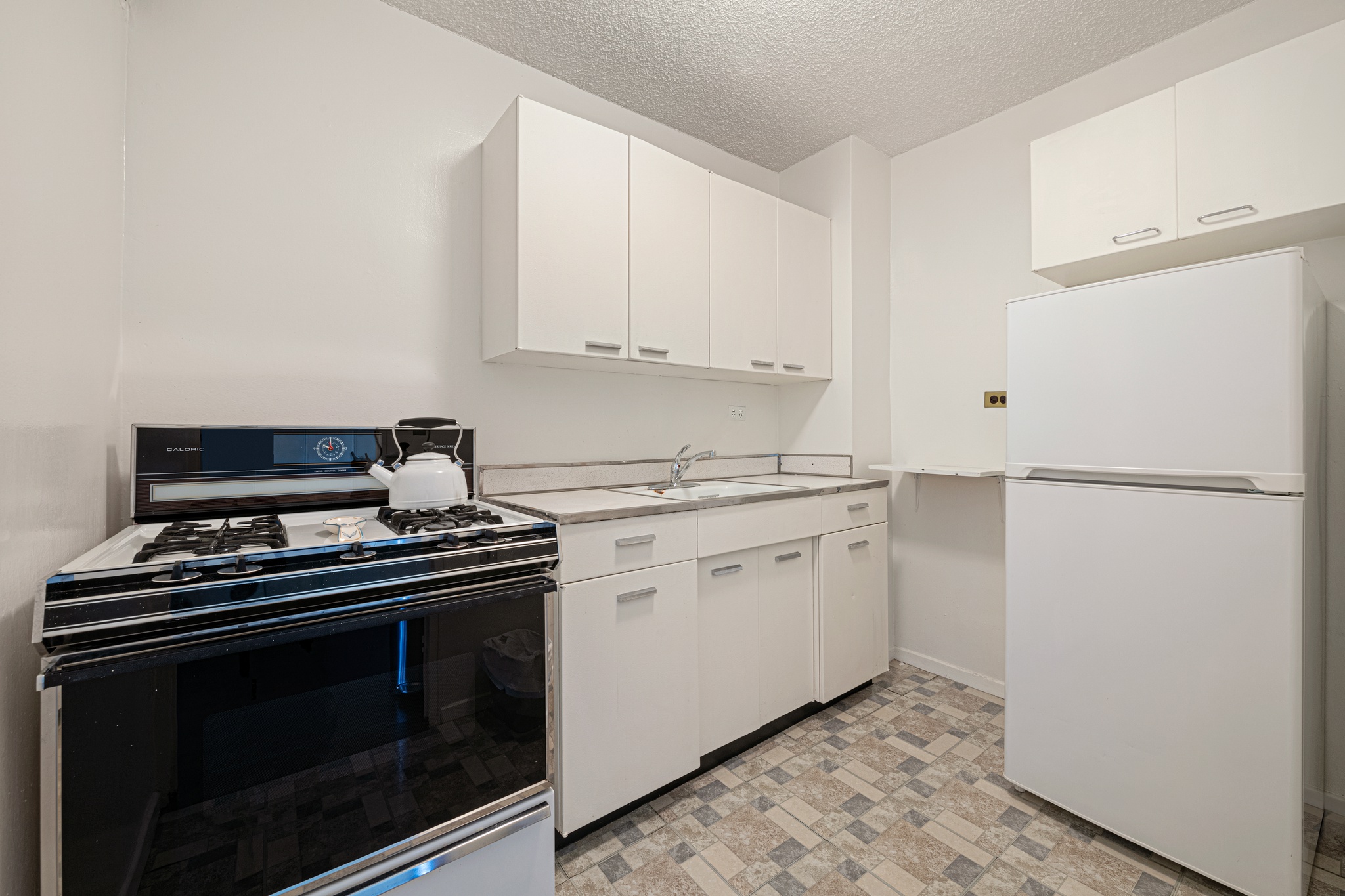 230 East 15th Street, Unit 7P Manhattan, NY 10003 - Photo 4 of 8 a kitchen with a stove and white cabinets