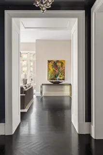 a view of an empty room and kitchen with wooden floor