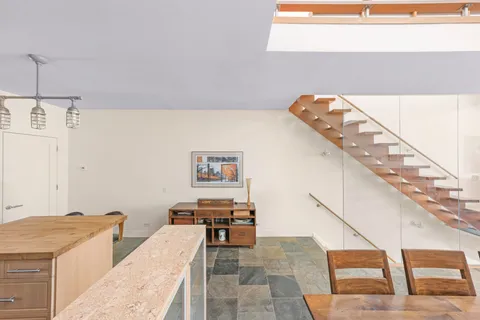 a open kitchen with stainless steel appliances kitchen island granite countertop a stove a sink a dining table and chairs with wooden floor