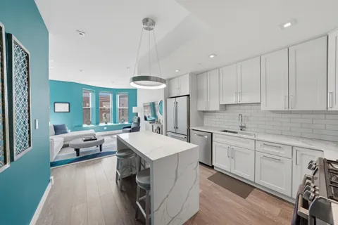 a large kitchen with white cabinets a sink dishwasher and a stove with wooden floor