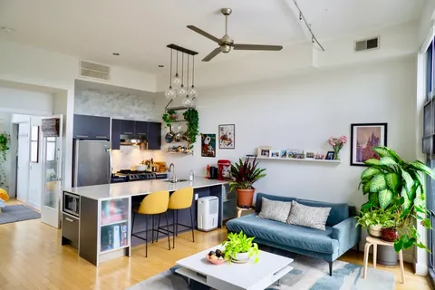 a living room with furniture kitchen view and a chandelier