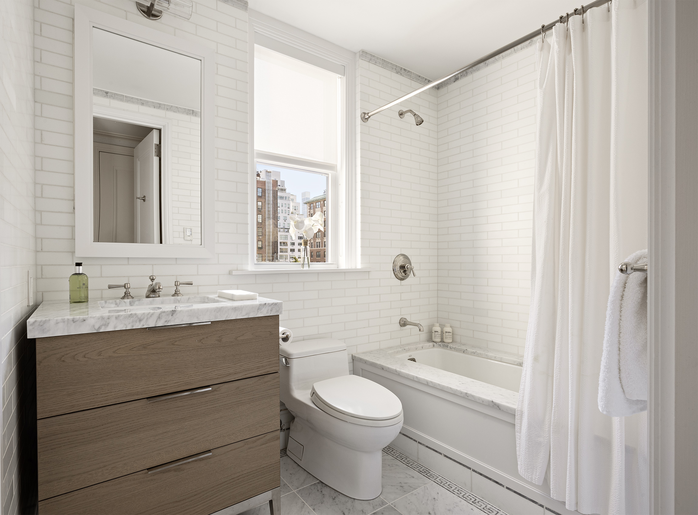 40 East 66th Street, Unit 9A Manhattan, NY 10065 - Photo 10 of 14 a bathroom with a toilet a sink a mirror a bathtub and vanity