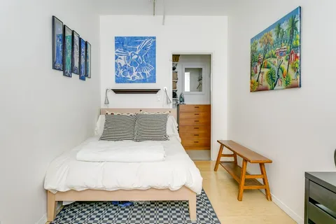 a white bed sitting in a bedroom next to a painting on the wall