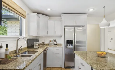 a kitchen with granite countertop a sink a counter space appliances and cabinets
