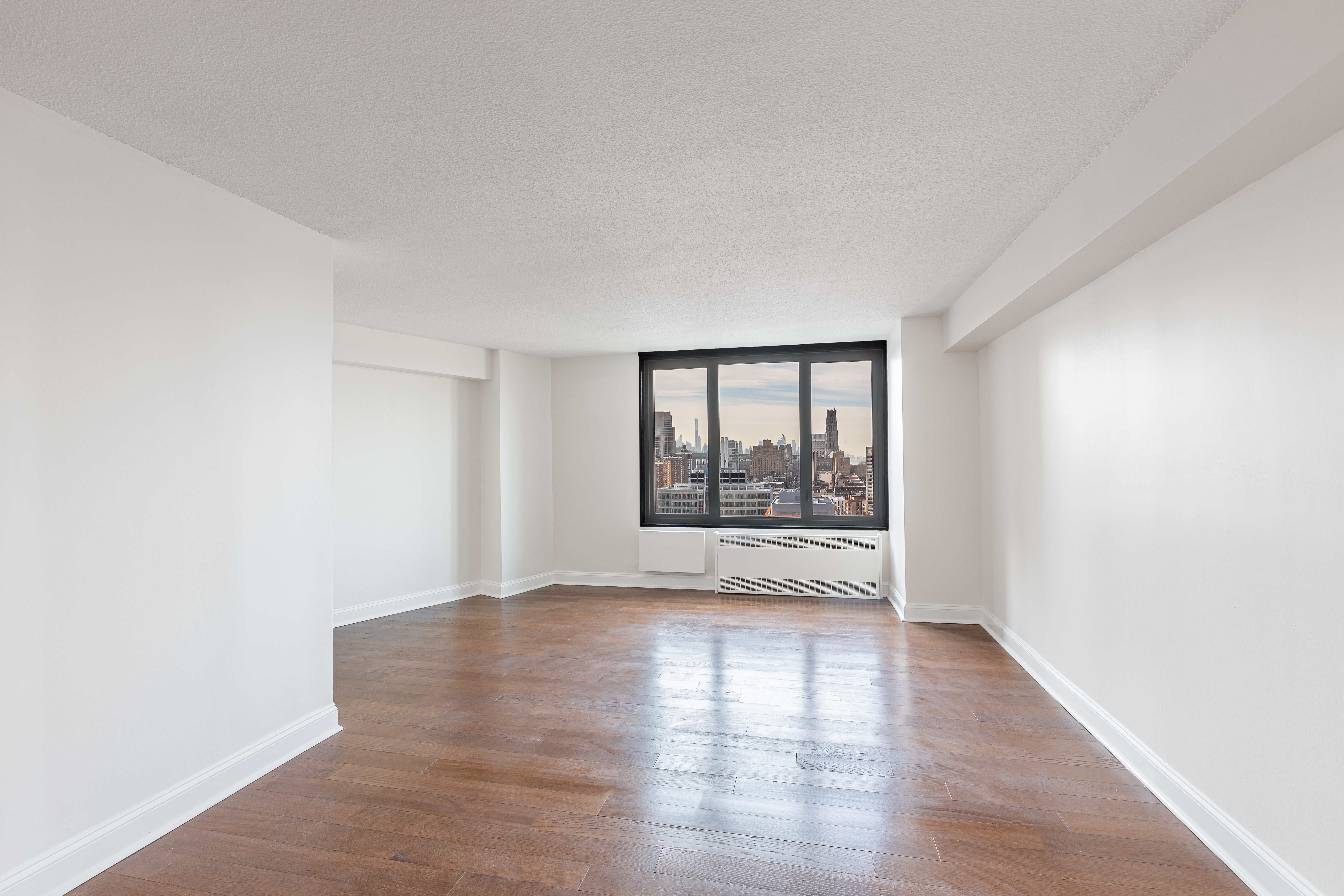 3333 Broadway, Unit B18C Manhattan, NY 10031 - Photo 2 of 23 a view of an empty room with a window and wooden floor