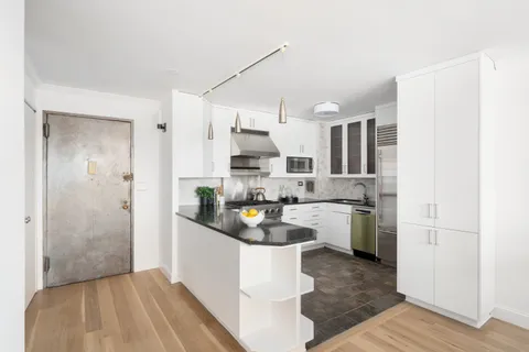 a kitchen with stainless steel appliances granite countertop a refrigerator a sink dishwasher a stove and white cabinets with wooden floor