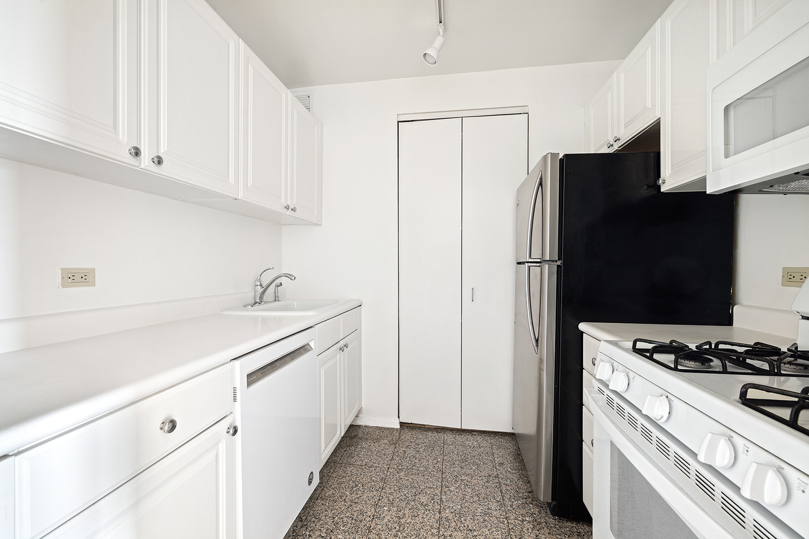 170 East 87th Street, Unit W15H Manhattan, NY 10128 - Photo 3 of 13 a kitchen with stainless steel appliances a refrigerator a sink and white cabinets