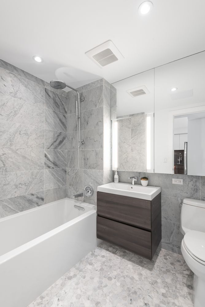 a bathroom with a bathtub toilet sink mirror and vanity