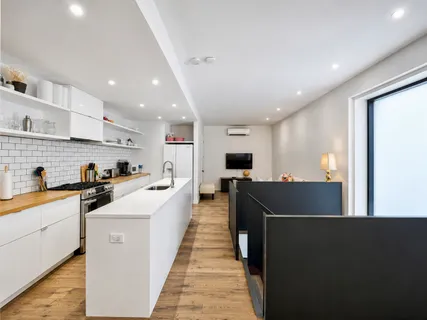 a view of a kitchen with kitchen island stainless steel appliances a sink and a living room view