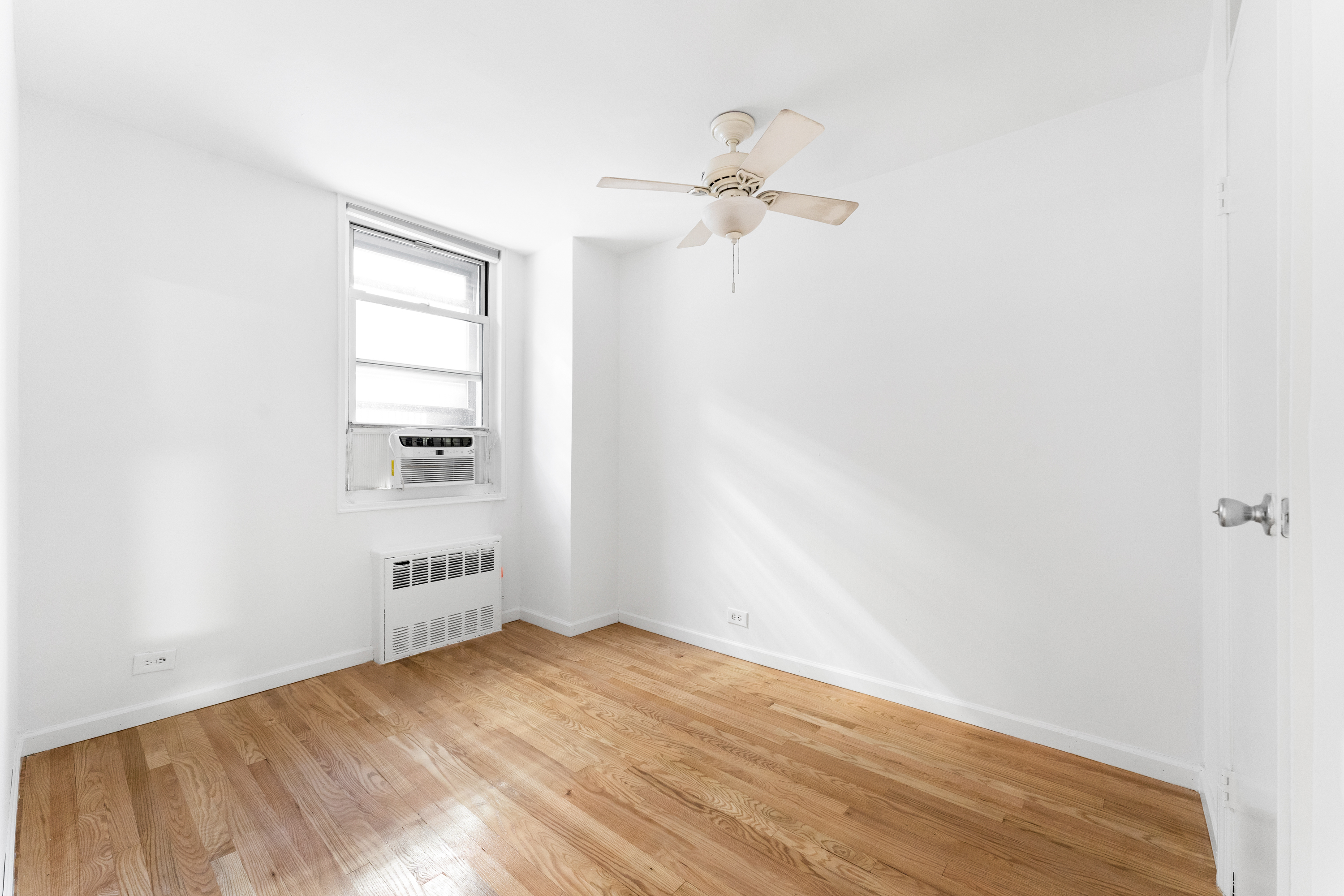 165 Christopher Street, Unit LV Manhattan, NY 10014 - Photo 7 of 16 an empty room with wooden floor cabinet and windows