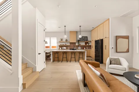 a living room with stainless steel appliances furniture and a kitchen view