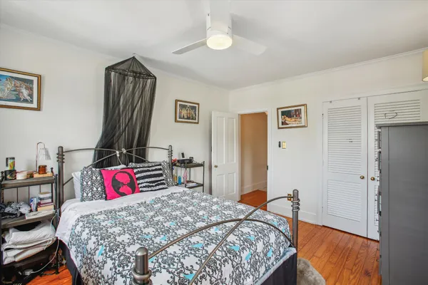 a bedroom with a bed and dresser with wooden floor
